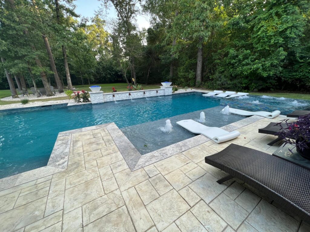 Rectangular custom pool with tanning ledge and raised spa in a Greater Houston backyard